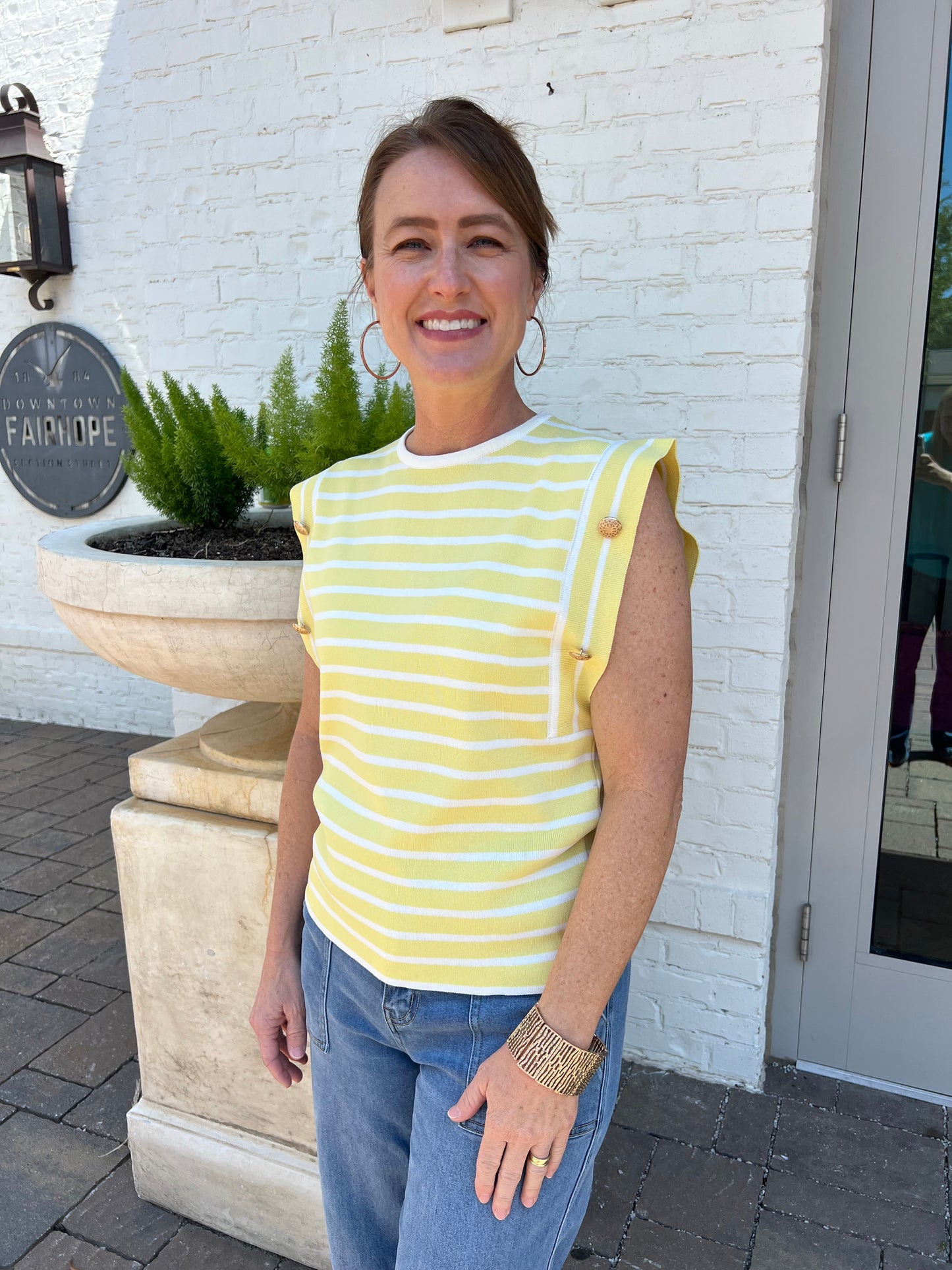 yellow sleeveless sweater top with gold buttons